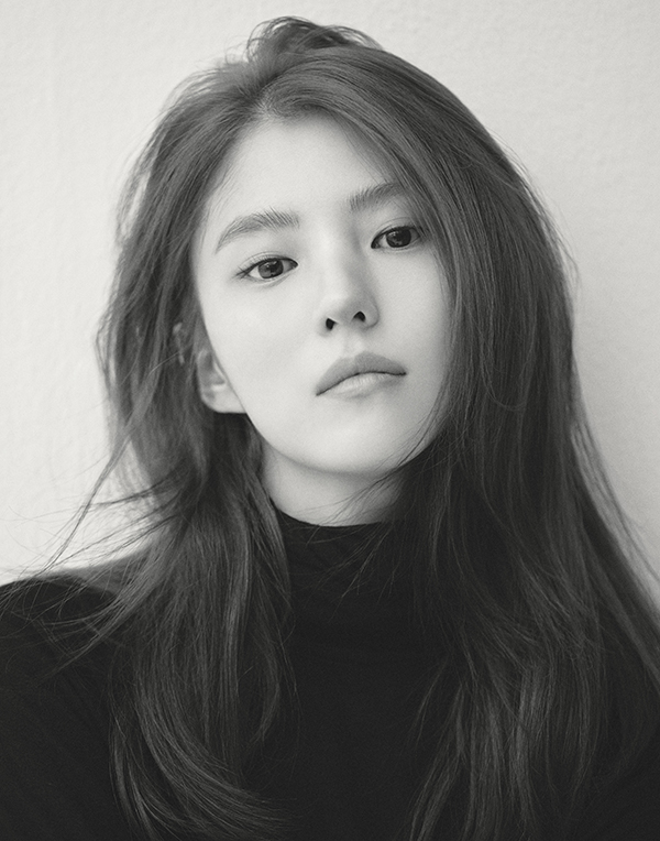 회색 배경 앞에서 검은 옷을 입고 카메라를 바라보는 한소희의 9아토엔터테인먼트 공식 프로필 사진